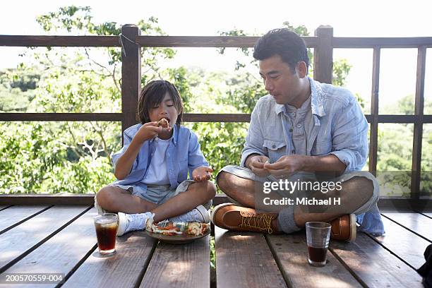father and son (8-9) in tree house, eating pizza - michael sit stock pictures, royalty-free photos & images