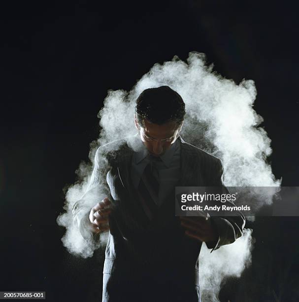 young businessman in dust cloud, looking down - shaking motion stock pictures, royalty-free photos & images