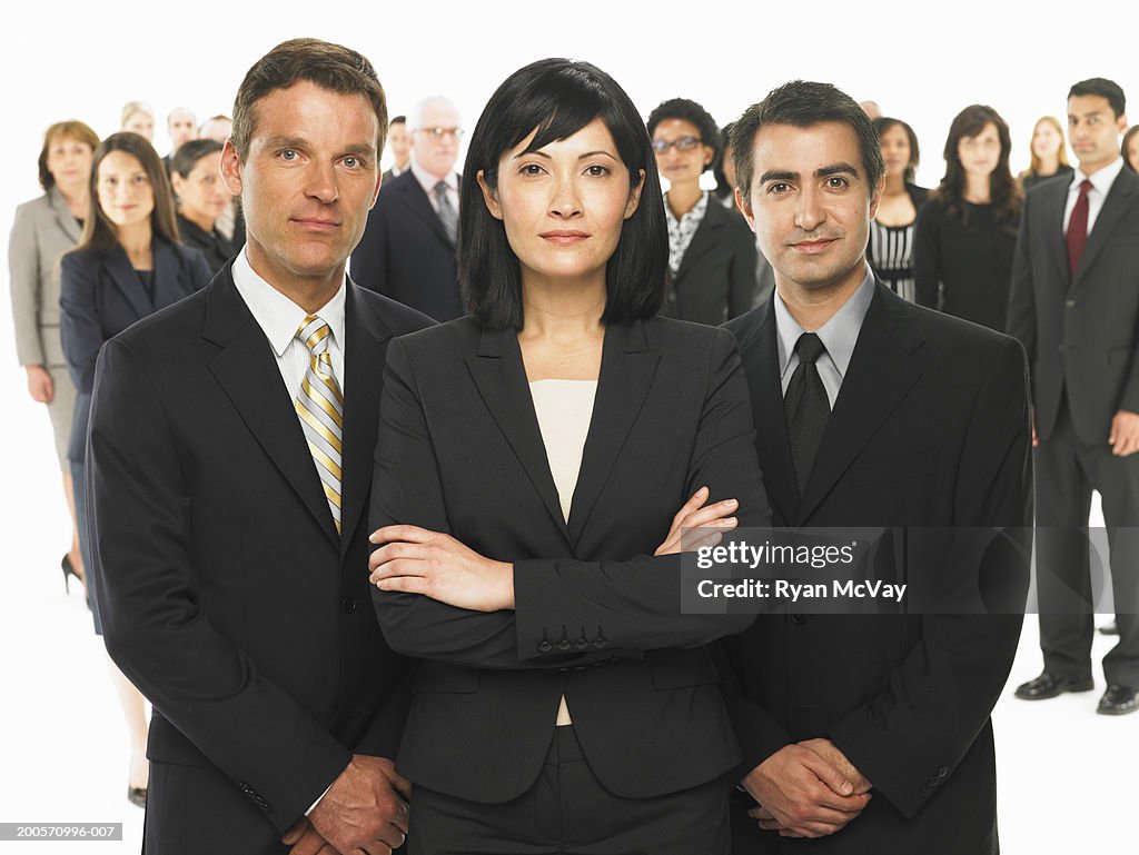Three business people standing in front of colleagues