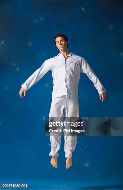 man floating in mid-air, eyes closed - pyjama fotografías e imágenes de stock