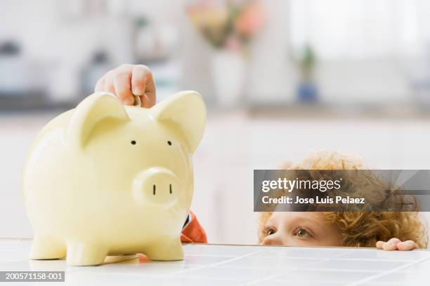 boy (4-5) putting money in piggy bank, close-up - boys money stock pictures, royalty-free photos & images