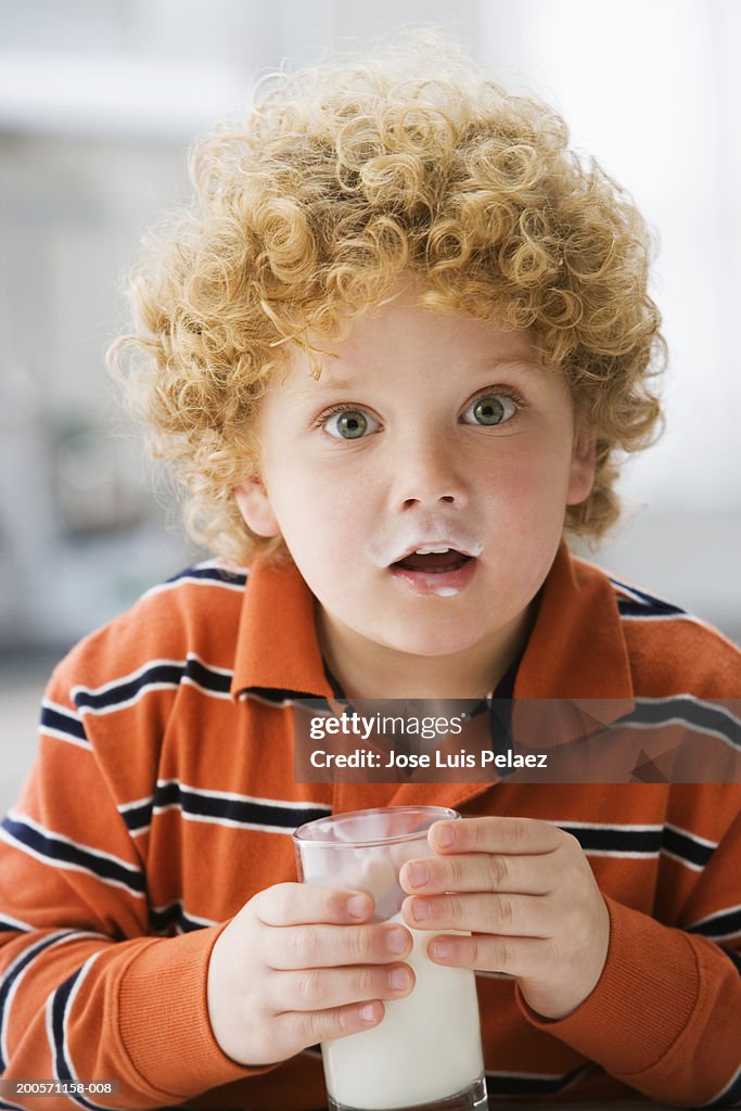 Boy (4-5) holding glass of milk, portrait, close-up