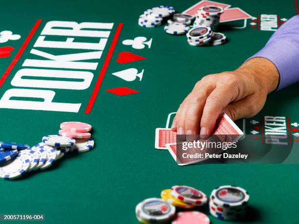 man looking at cards at poker table, close-up of hand - black jack hand stock-fotos und bilder