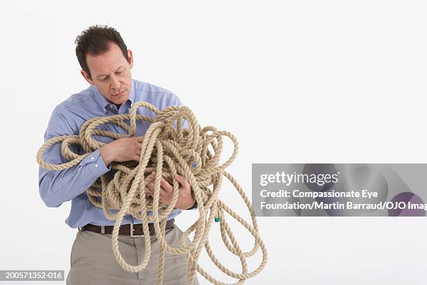 mature man holding entangled rope - embaraçado - fotografias e filmes do acervo