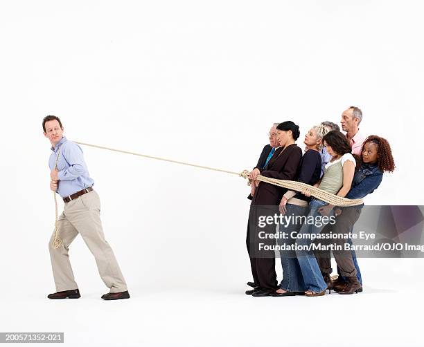 man pulling group of people tied up with rope - pulling stockfoto's en -beelden