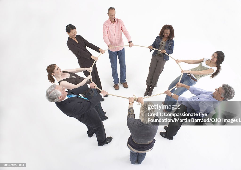 Group of people standing in circle, holding rope, elevated view