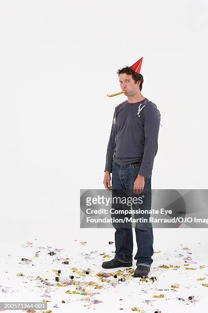 man wearing party hat, blowing party blower, portrait - futility stock pictures, royalty-free photos & images