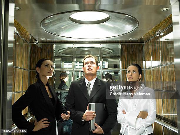 three business colleagues standing in elevator - 3 men looking up stock pictures, royalty-free photos & images