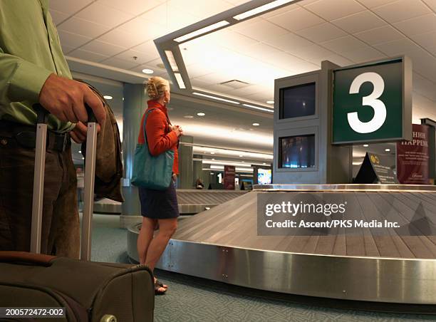 woman waiting at baggage carousel in airport - angeleuchtet zahlen mensch stock-fotos und bilder