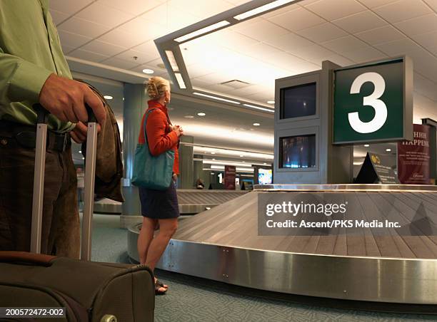 woman waiting at baggage carousel in airport - baggage claim stock pictures, royalty-free photos & images