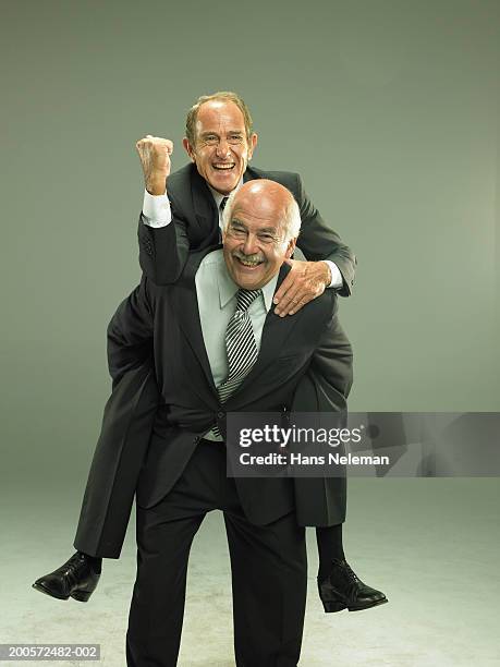 senior business man giving colleague piggy back, portrait - piggy back stockfoto's en -beelden