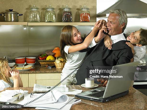 business man with children (6-10)using laptop and telephone in kitchen - landline phone home stock pictures, royalty-free photos & images