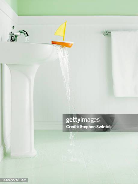 bathroom with overflowing sink and child's toy boat on edge of sink - overflowing fotografías e imágenes de stock