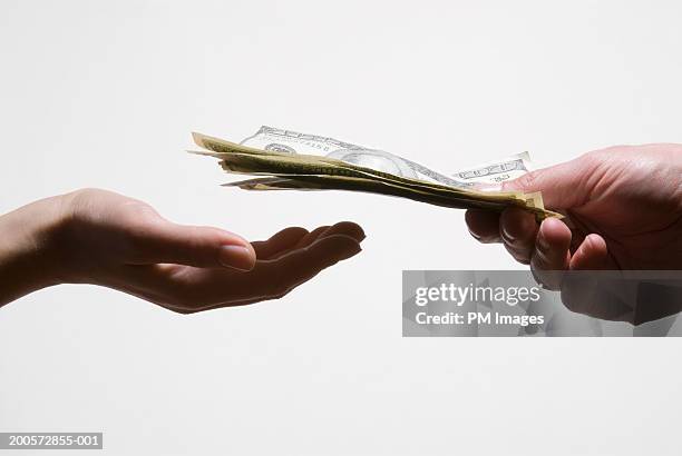 man handing woman us dollar banknotes, close-up - busta paga foto e immagini stock