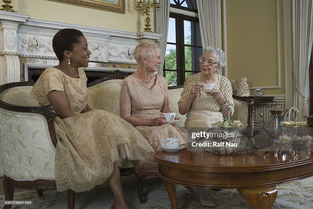 Two senior women and mature woman having tea