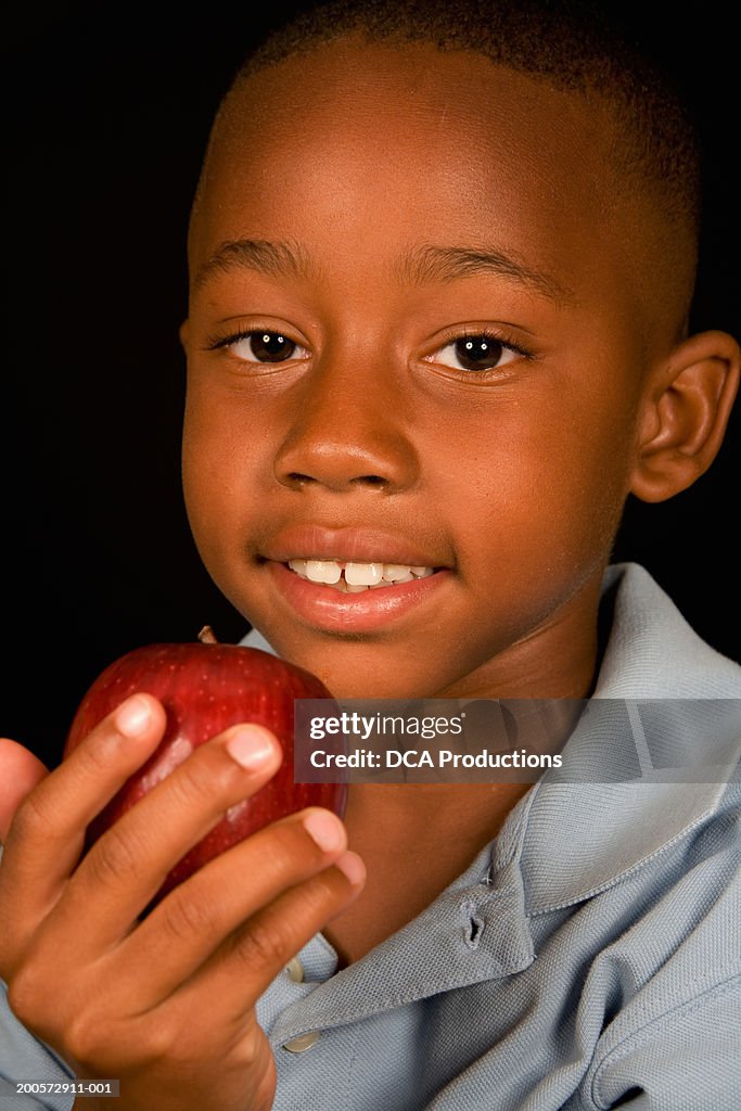 Boy (6-7) holding apple, portrait, close-up