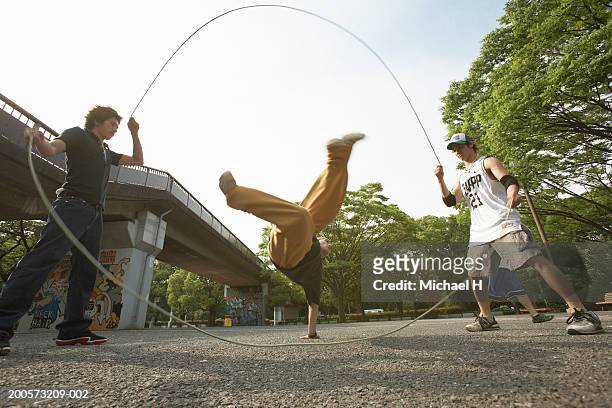 young men playing double dutch, low angle view - springtouw stockfoto's en -beelden