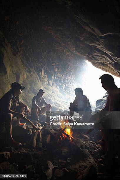 men sitting around fire in cave - cave fire 個照片及圖片檔