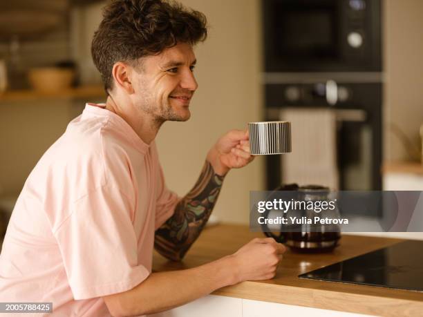 a man is resting at home, drinking tea in the kitchen - un seul homme photos et images de collection