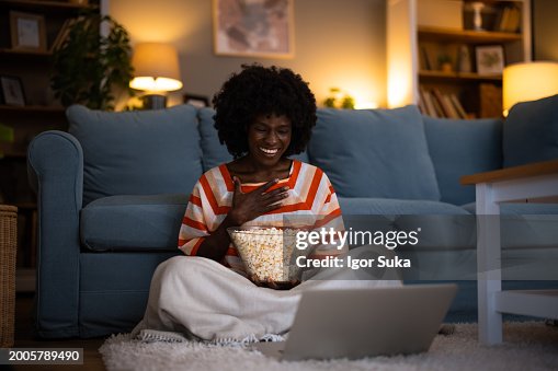 Young multiracial woman watching movie at home eating popcorn Young multiracial woman watching movie at home eating popcorn