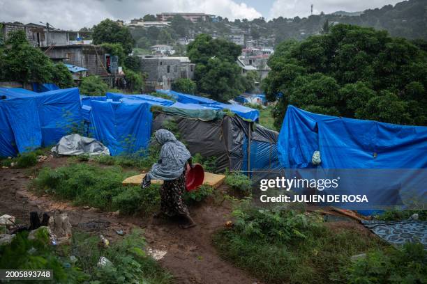 Woman walks on a muddy pathway along shelter tents in a makeshift camp where migrants live at the Cavani stadium in Mamoudzou on the French island of...