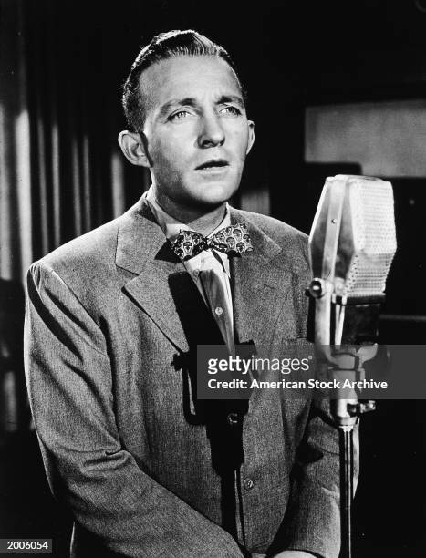 American actor and singer Bing Crosby sings into a microphone, circa 1945.