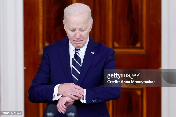 President Joe Biden looks at his watch as he arrives to give remarks with King of Jordan Abdullah II ibn Al Hussein at the White House on February...