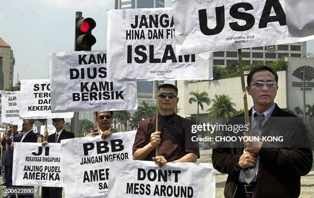 Indonesian Muslims hold placards reading "American go to hell, Islam is not terrorists, Don't mess around with Islam" during a protest along a street...