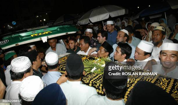 Singaprean muslim men carry one of the Irian twins sister coffin into the hearse van to be send to the airport for departure to Iran at the Ba'Alwi...