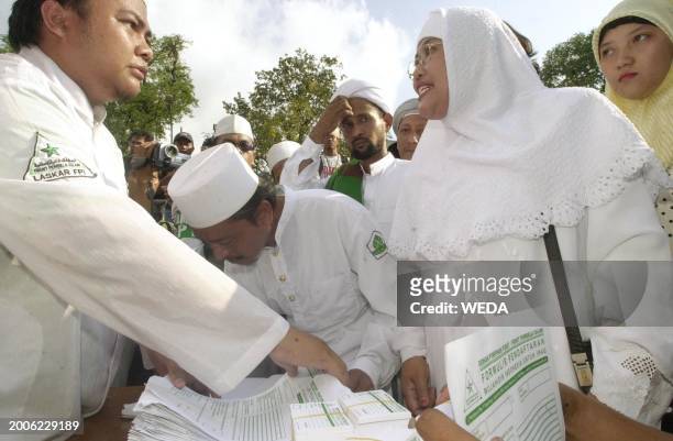 An Indonesian Muslim woman ask information from an official of the militant Muslim hardline group, Front for the Defender of Islam , who man a...
