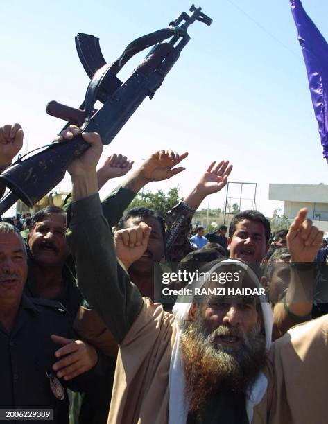 Sunni Muslim cleric waves a Kalashnikov during an anti-US demonstration in the Iraqi city of Tikrit, the birth place of Iraqi President Saddam...