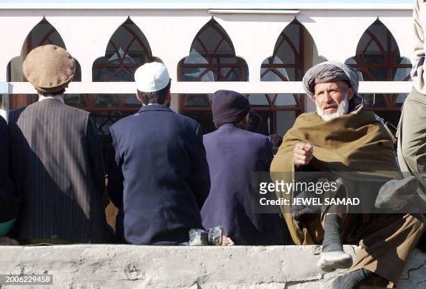 An elderly Afghan man removes his shoes to join special prayers at the start of the Eid al-Adha festival, 11 February 2003 in Kabul. The Eid al-Adha...