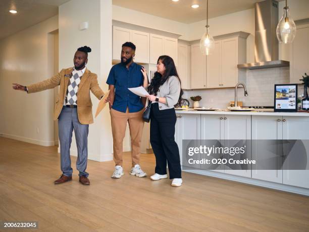 real estate agent showing a new home to prospective buyers - visita de inmuebles en venta fotografías e imágenes de stock