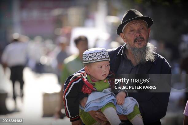 Oly-2008-China-unrest-Xinjiang-security by Dan Martin An ethnic Uighur grandfather carries his grandson on a street in Aksu in China's far western...