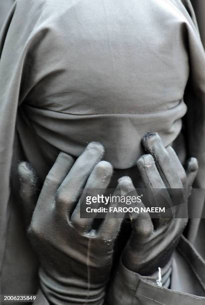 Burqa wearing Pakistani female religious student prays for the martyrs of the Red Mosque as she sit on the debris of Jamia Hifza seminary in...