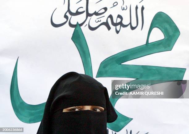 Female activist of Pakistan's main hardline Islamic party Jamaat-e-Islami stands beside a placard as she participates in a rally to mark the...