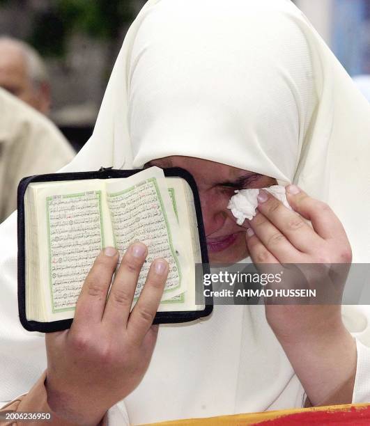 An Egyptian Muslim woman holding the holy Koran, wipes her tears 18 April 2004, during a demonstration in the northern port city of Alexandria...