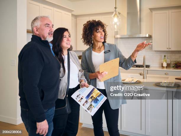 real estate agent showing a new home to prospective buyers - real estate agent stock pictures, royalty-free photos & images