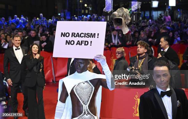 Papis Loveday carrying a banner written 'No Racism! No AfD' attends the 'Small Things Like These' premiere and Opening Red Carpet during the 74th...