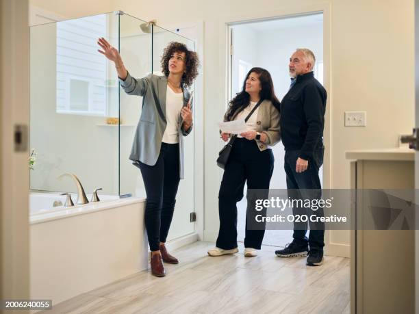 real estate agent showing a new home to prospective buyers - new bathroom stock pictures, royalty-free photos & images