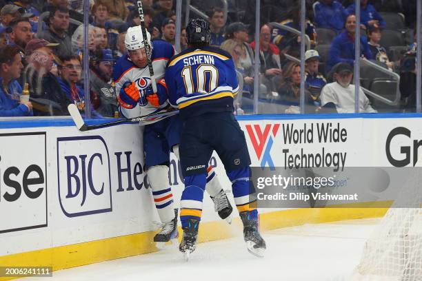 Brayden Schenn of the St. Louis Blues checks Cody Ceci of the Edmonton Oilers during the first period at Enterprise Center on February 15, 2024 in St...