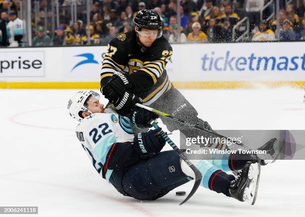 Hampus Lindholm of the Boston Bruins checks Oliver Bjorkstrand of the Seattle Kraken off the puck during the second period at TD Garden on February...