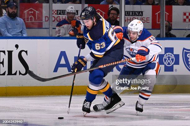 Zach Hyman of the Edmonton Oilers battles Jake Neighbours of the St. Louis Blues for the puck on February 15, 2024 at the Enterprise Center in St....