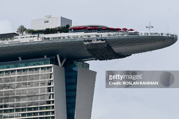 People stand along the top of the Marina Bay Sands observation deck in Singapore on February 16, 2024.