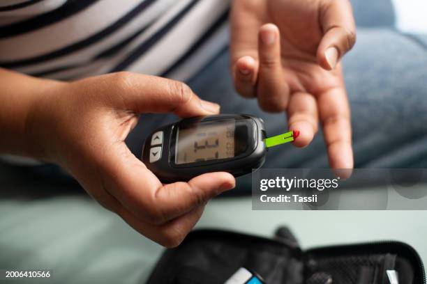 glucometer, lancet and hands in closeup for blood, test and reading for numbers, wellness and sugar level. machine, needle and person with diabetes with screen to monitor glucose in home for health - glucose stockfoto's en -beelden