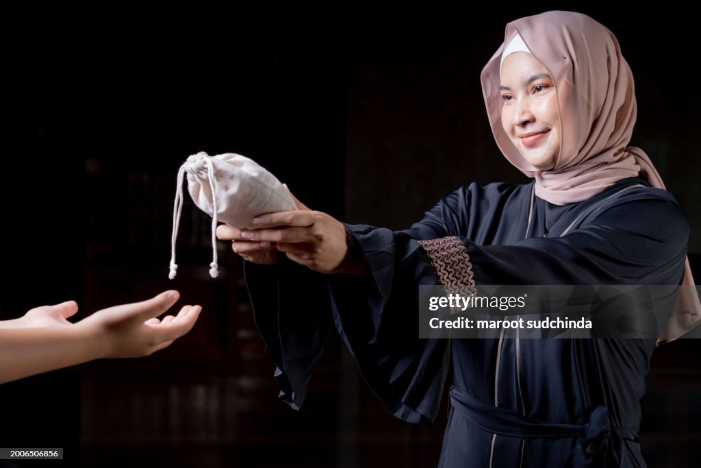 Hands holding a money bag for zakat, Islamic zakat concept. Muslims help the poor and needy.