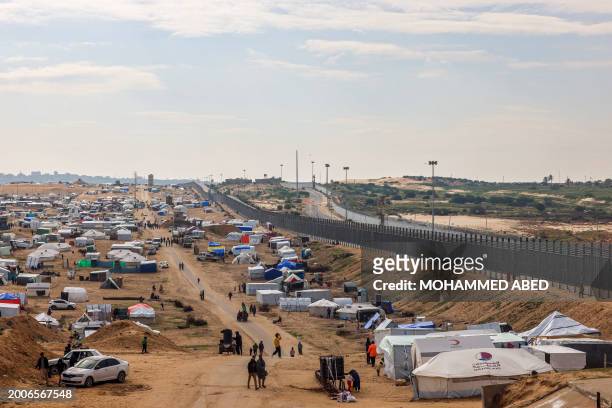 Displaced Palestinians camp near the border fence between Gaza and Egypt, on February 16, 2024 in Rafah, in the southern Gaza Strip, amid the ongoing...