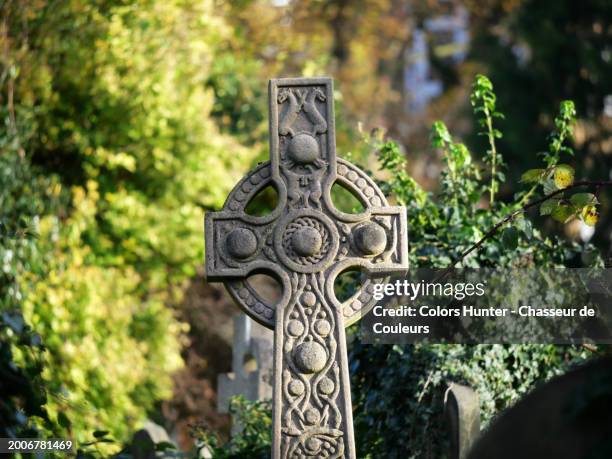 close-up of an ancient celtic stone cross decorated with dogs and snakes. photograph taken at brompton cemetery in london, england, united kingdom. sunlight. natural colors. - celtic style stock pictures, royalty-free photos & images