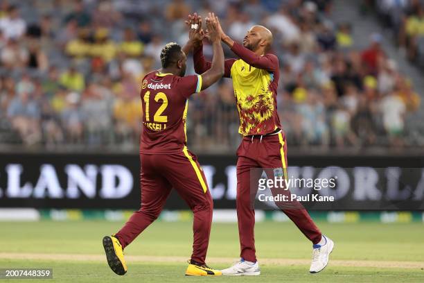Andre Russell and Roston Chase of the West Indies celebrate the wicket of JIduring game three of the Men's T20 International series between Australia...