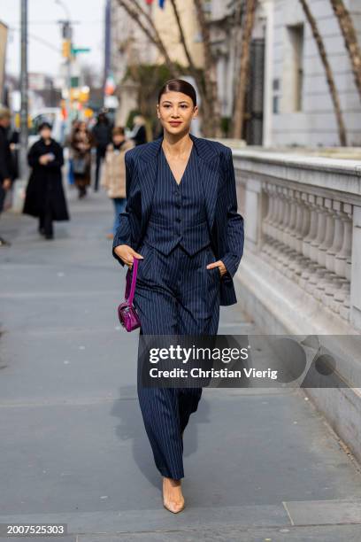 Guest wears navy striped blazer, pants, vest outside Coach on February 12, 2024 in New York City.